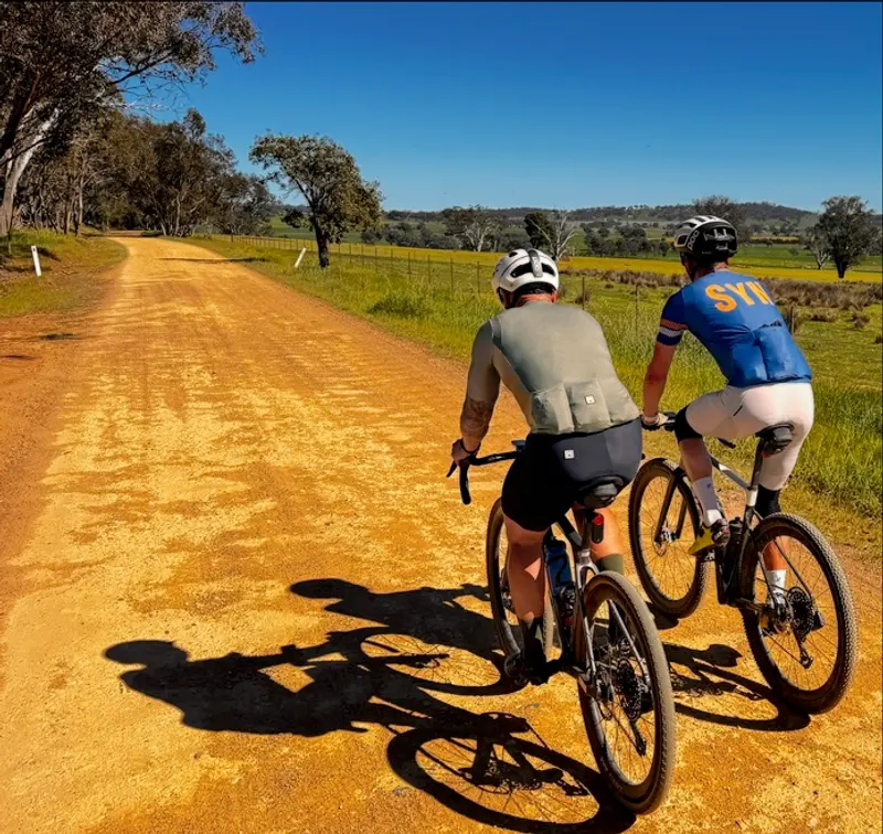 Two gravel riders side by side on a dirt road through farmland near Mudgee