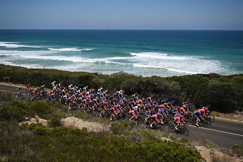 A group of riders on a coastal road beside the ocean.